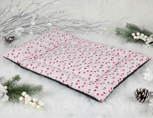 Cama colchoneta con corazones rosas en escena navideña de producto